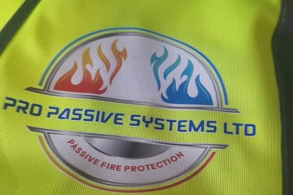 Close-up of the Pro Passive Systems Ltd logo printed in full colour on yellow hi-vis: red and blue flames above the company name and the words Passive Fire Protection