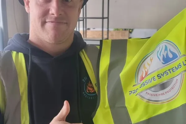 Luke holding the yellow hi-vis vest with its grey reflective bands and the printed company logo